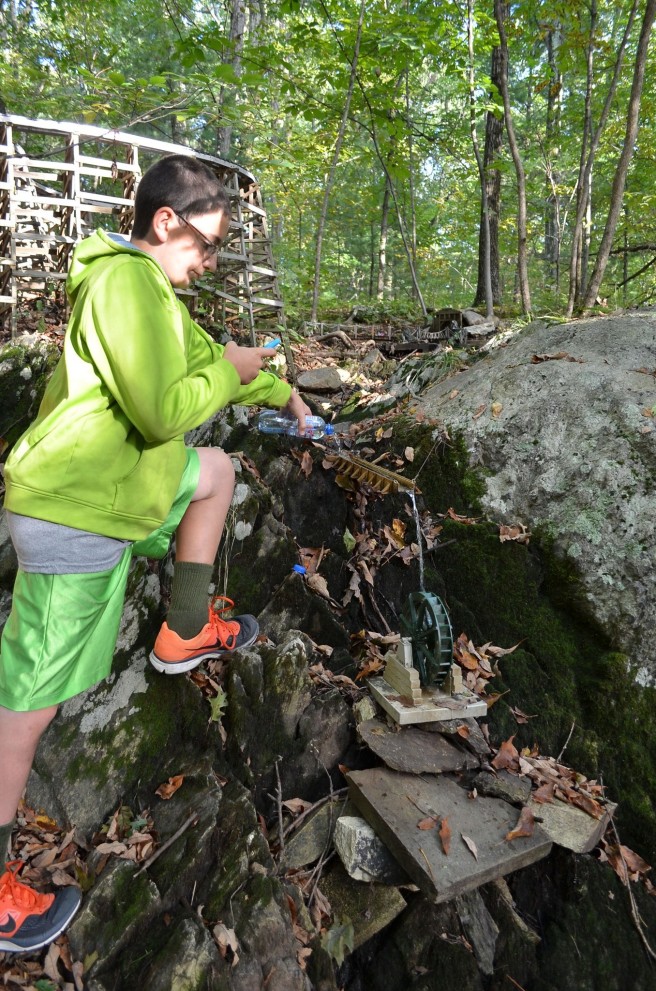 A young geocacher testing out the waterfall and waterwheel.