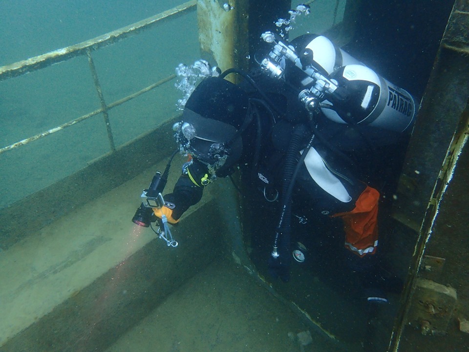 A scuba diver underwater investigates a sunken ship